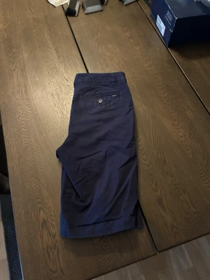 Mörkblå chinosshorts med fickor från Ralph lauren - Snygga mörkblå shorts i chinos med klassisk design. De har en bakficka med knapp och raka ben. Perfekta för varma dagar och enkel att matcha med olika stilar.