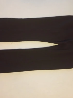 Svarta kostymbyxor med pressveck - Snygga svarta kostymbyxor med klassiskt pressveck och rak passform. Perfekta för en stilren look. Materialet ser ut att vara ett mjukt tyg som ger en dressad känsla.