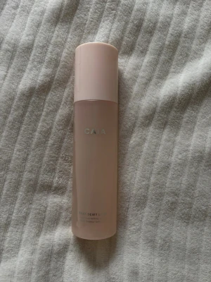 CAIA Dewy Look Face Mist - Fräsch face mist från CAIA i en stilren, cylinderformad flaska med matt ljusrosa färg och vitt tryck. Perfekt för att ge huden en återfuktad och glowig finish. Flaskan är gjord av plast och har en praktisk sprayfunktion.