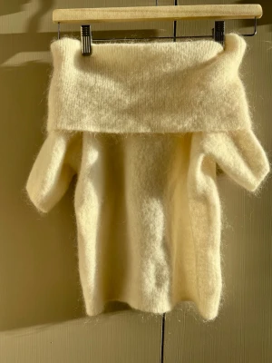 Offwhite stickad tröja med stor krage - Mysig offwhite stickad tröja med oversized polokrage och kortare ärmar. Tröjan har en fluffig och mjuk känsla, perfekt för lager-på-lager. Passar dig som gillar en avslappnad och trendig stil.