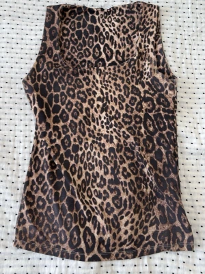 Leopardmönstrad linnetopp från Zara - Snygg leopardmönstrad linnetopp från Zara i mjukt, glansigt material. Toppen är ärmlös och har en rund halsringning. Perfekt för dig som vill sticka ut med ett djurmönster i garderoben.