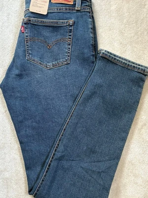Blå Levi's skinny jeans - Snygga blå skinny jeans från Levi's med klassisk femficksdesign och tydliga kontrastsömmar. Jeansen har en hög midja och smal passform hela vägen ner. Tillverkade i mjukt och stretchigt denim för extra komfort. Perfekta till en avslappnad och trendig look.