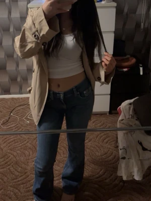 Blå bootcut jeans med låg midja  - Säljer ett par blå bootcut jeans med låg midja och klassisk femficksdesign. Jeansen har en snygg tvätt och sitter tajt upptill med utsvängda ben. Perfekta till crop tops och sneakers för en trendig look.