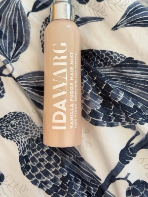 IDA WARG Vanilla Fudge Hair Mist - Fräsch hårmist från IDA WARG med doft av vanilj och fudge. Kommer i en beige plastflaska med silverfärgat lock. 100% vegansk och fungerar som en hårparfym som ger håret en söt och fräsch doft.