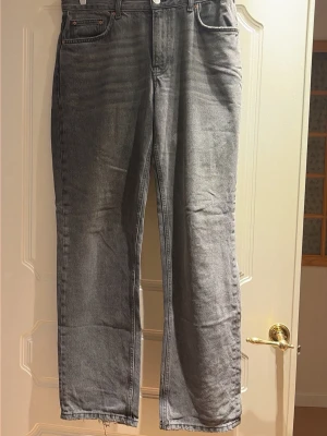 Grå raka jeans - Säljer ett par grå jeans med rak passform.  Jeansen har klassisk femficksdesign och är tillverkade i denim. Perfekta för en avslappnad och trendig look.