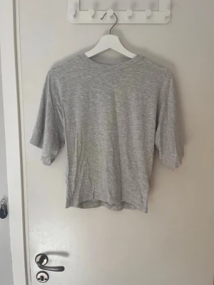 Grå basic t-shirt från 157 - Enkel och stilren grå t-shirt från 157 i mjuk bomull. T-shirten har rund halsringning och korta ärmar, perfekt för en avslappnad look. Passformen är normal och tyget är lätt och skönt mot huden.