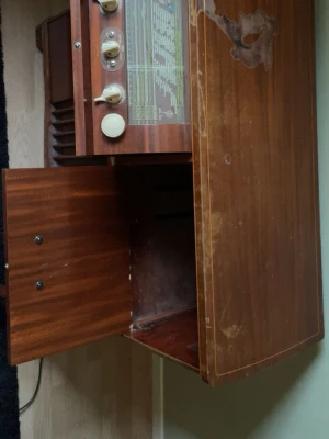 Retro radiomöbel i trä - Säljer en vintage radiomöbel i mörkt trä med klassiska vred och glasruta med radiokanaler. Möbeln har flera förvaringsfack och en snygg retrodesign som passar perfekt för dig som gillar gammal elektronik och inredning med karaktär.
