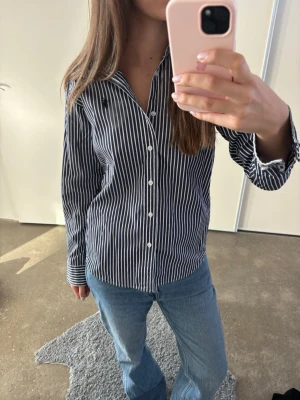 Randig skjorta från Ralph Lauren - Snygg blå och vit randig skjorta från Ralph i bomull. Passar dig som har storlek S/M