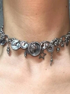 Silverfärgat armband med berlocker - Säljer ett coolt armband i silverfärgad metall med flera runda berlocker och en stjärna. Armbandet har chunky länkar och detaljer som ger en edgy och trendig look. Perfekt för dig som gillar unika accessoarer med mycket attityd.