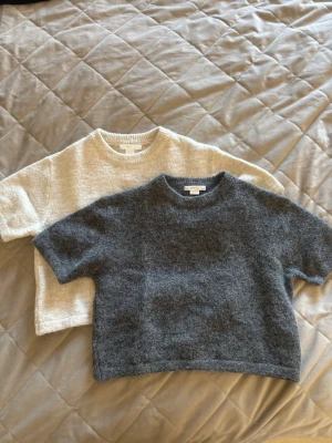 Två stickade t-shirts från Gina tricot Young  - Säljer två stickade t-shirts från Gina tricot Young , en i grått och en i offwhite. Båda har korta ärmar, rund halsringning och är gjorda i ett mjukt, fluffigt material. Tröjorna är i storlek 134/140💞