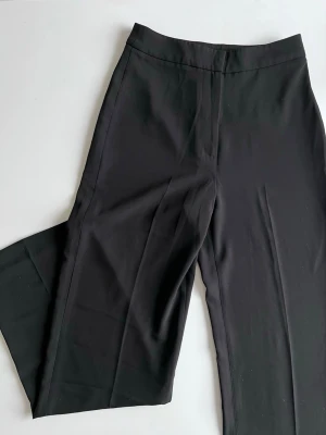 Svarta kostymbyxor från H&M, stl 34 – nyskick! - Svarta kostymbyxor i storlek 34, inköpta i Australien och använda en gång. Fina till en enkel topp, kavaj och klackar eller y2k-vibe med baby tee. Midja: 69-70cm Innerlängd: 79cm  Superbekväma! Nypris: 399kr  Säljes vidare i nyskick så att någon annan kan få använda dem mer ✨ 