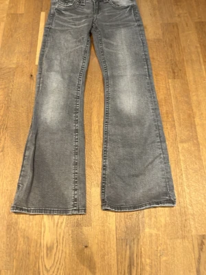 Grå bootcut jeans från Gina Tricot - Säljer ett par grå bootcut jeans från Gina Tricot med dubbla knappar. Storlek 152. Bra skick