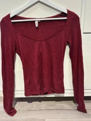 Mörkröd långärmad topp - Mörkröd långärmad topp från nelly med croppad passform och lätt v-ringad halsringning. Tillverkad i mjuk bomull med en enkel, stilren design och diskret kantdetalj vid halsen. 