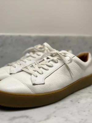 Tiger of Sweden Salas Sneaker – Vit – Stl 44 - Säljer ett par exklusiva sneakers från Tiger of Sweden, modell Salas (artikel U6432003 090).  Mycket fint skick. Minimal slitning på sula och inga skador på lädret. Tillverkade i Portugal i premiumläder med ljus gummisula.  Nypris ca 2 500 kr.  Storlek: 44 Färg: Vit Skick: Mycket gott skick  Pris: 2000kr  Skickas eller möts upp.