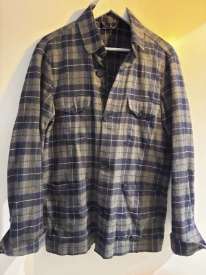 La Chemise Overshirt - Overshirt i mjukt tyg med blå och grå rutor. Klassisk krage, knäppning framtill och fyra fickor – två på bröstet med lock och två nedtill. Perfekt lager-på-lager-plagg med avslappnad passform och raka ärmar.