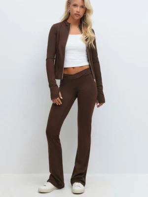 Brunt loungewear-set med zip-jacka - Säljer ett brunt loungewear-set med figurnära zip-jacka och matchande byxor med utsvängda ben. Jackan har långa ärmar med tumhål och diskreta sömdetaljer. Materialet ser ut att vara mjukt och stretchigt, perfekt för chill dagar hemma.
