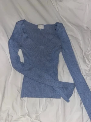 Ljusblå ribbad långärmad topp - Snygg ljusblå ribbad topp med lång ärm och rundad urringning. Perfekt att styla med jeans eller kjol för en enkel men trendig look. Materialet är stretchigt och följsamt för en bekväm passform.