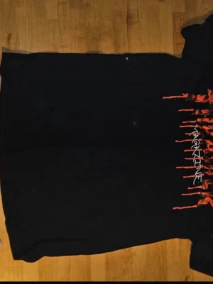 Svart t-shirt med tryck från trasher - Cool svart t-shirt från trasher med ett grafiskt tryck i rött och vitt på framsidan. Klassisk passform och rund halsringning, perfekt till jeans eller shorts. Materialet känns mjukt och bekvämt mot huden.