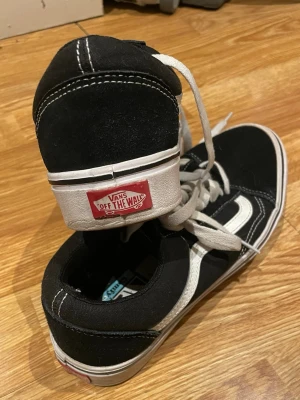 Svarta Vans Sk8-Hi sneakers - Klassiska Vans Sk8-Hi sneakers i svart canvas och mocka med vit sidestripe och vita snören. Skorna har hög modell och tydlig Vans-logga på hälen. Perfekta för en streetwear-look och funkar året runt. Använda men utan defekter alls. Använd gärna köp nu