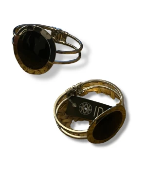 Silvrigt armband med svart detalj - Snyggt armband från LENE IDAR med rund, svart detalj i mitten och silverfärgad metall. Armbandet har en öppen design med två parallella band och ett spänne. Perfekt för dig som vill ha en statement-accessoar med modern känsla.