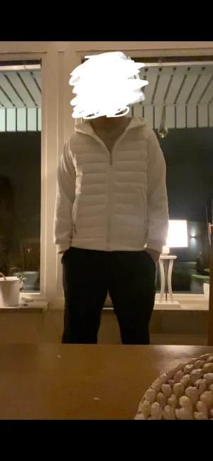 Vit Cardigan  - Säljer en fräsch vit Cardigan med huva och dragkedja framtill. Jackan har quiltad design och två sidofickor. Perfekt för dig som vill ha en clean och stilren look under kyliga dagar. Passar dig som gillar enkel och modern stil.