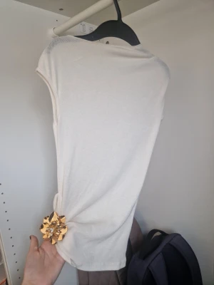 Vit ärmlös linnetopp - Snygg vit ärmlös linnetopp med enkel och clean design. Toppen har rund halsringning och är gjord i ett mjukt, tunt material som känns skönt mot huden. Perfekt att styla med jeans eller kjol för en fräsch look.