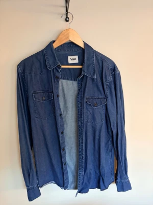Acne skjorta - Säljer min snygga Acne skjorta. Det är en klassisk stilren jeans skjorta som passar till mycket. Skjortan är i fint skick.