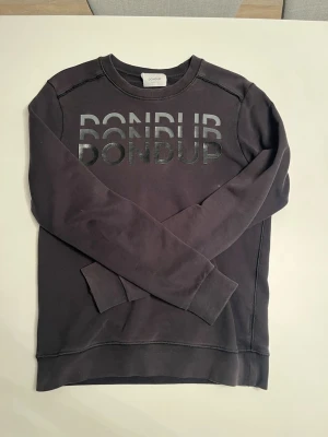Svart sweatshirt från Dondup - Tvärfet svart sweatshirt från dondup i storlek S.                OBS! 🚨 Små slitningar på rygg och på vänster ärm (inget man märker av)                                                                    Hör av dig om du har frågor! 💭                                         Modell är 183cm 68kg 💫 