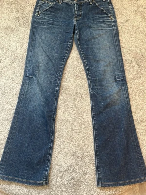 Blå bootcut jeans från Yanük - Säljer mina jeans från Yanük. Jeansen har framfickor med nitar och bakfickor med lock och knappar.Med gula och bruna markerade sömmar . Tyvärr har personen jag köpte dem av klipp av lappen med storleken, tror att de e 36/38 midjan är 38 o längden är 102,5