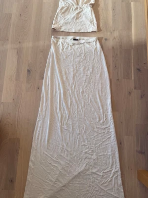 Kjol och topp sett  - Beiget sommrigt kjol och topp sett. Toppen är halterneck och knyts i nacken. Super stretchigt material från gina tricots soft toutch collection Perfekt till sommaren. 
