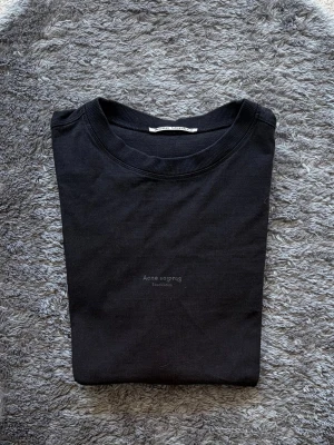 Acne Studios Reverse Logo T-Shirt Svart (Fits M/L) - Riktigt fet t-shirt från Acne Studios med deras reverse logo 🔥 Oversized fit som sitter sjukt bra och ger en clean men ändå statement look.  Storlek S men passar lätt M/L tack vare passformen. Mycket fint skick!