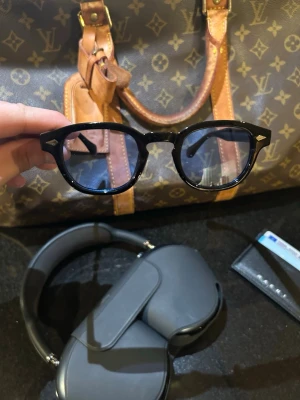 Solglasögon med ljusblått glas  - Snygga och trendiga svarta solglasögon med en klassisk form. De har blåa linser och en stilren design som passar perfekt för soliga dagar. ☀️ En tidlös accessoar för den modemedvetna. Skicka 10/10. Priset är inte hugget i sten så skicka gärna prisförslag✅ Skriv vid frågor eller funderingar i DM🍾