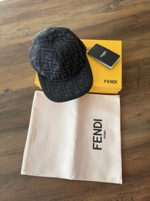 Svart keps med FF-mönster - Snygg svart keps med ikoniskt FF-mönster över hela kepsen. Klassisk böjd skärm och justerbar baksida. Kepsen är tillverkad i ett slitstarkt material och levereras med originalbox och dustbag.