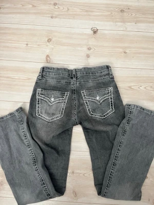 Grå bootcut jeans med kontrastsömmar - Säljer ett par grå bootcut jeans med vita detaljer. Bra skick. Använda max 3 gånger. 