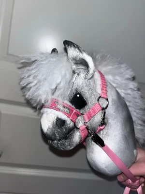 Käpphäst - Säljer en käpphäst med mjuk, grå päls och vit man. svart tyg runt ögonen. Perfekt för lekar och hobby horse-tävlingar. Lång käpp i trä för enkel användning.