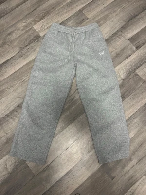 Gråa gym/mjukisbyxor från VICI - Säljer ett par gråa mjukisbyxor från VICI med bred passform och resår i midjan samt snörning. Byxorna har ett diskret tryck på vänster höft och är tillverkade i mjukt bomullsmaterial. Perfekta för chill och avslappnade dagar eller på gymmet. Stolen XL men liten i storleken så bara skriv om du vill ha mått!