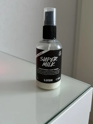 LUSH Super Milk hårprimer  - LUSH Super Milk Conditioning Hair Primer. Produkten är en leave-in hårprimer som hjälper till att återfukta och reda ut håret. Snygg och enkel design med svart etikett.