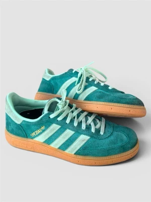 Adidas Spezial gröna mocka sneakers - Säljer ett par Adidas Spezial sneakers i grön mocka med klassiska vita ränder och gummisula. Skorna har mintgröna skosnören och detaljer samt guldfärgad Spezial-logga på sidan. Perfekta för dig som gillar retrostil och streetwear.