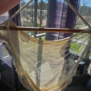 Makramé hängstol i beige bomull - Säljer en snygg makramé hängstol i beige bomull med träpinne upptill. Perfekt att hänga upp på balkongen eller i ett rum för en chill vibe. Stolen har ett nätmönster och rejäla rep för upphängning.