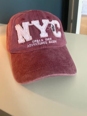 Vinröd NYC keps. - Säljer en fet vinröd keps som är i nästan helt nytt skick!!