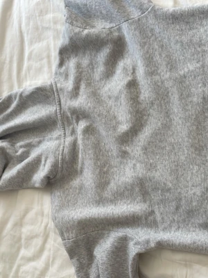 Grå basic hoodie med ficka - En klassisk grå hoodie i mjukt material med huva och stor magficka. Tröjan har ribbade muddar vid ärmslut och nederkant. Perfekt för en avslappnad och stilren look.