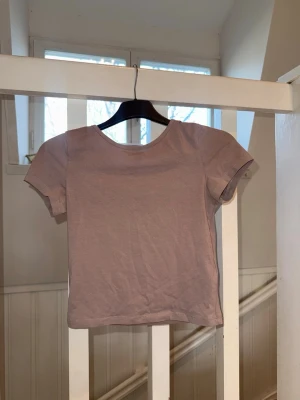 Ljuslila croppad t-shirt - En enkel och stilren ljuslila t-shirt med croppad passform och rund hals. T-shirten har korta ärmar och är tillverkad i mjuk bomull, perfekt för en avslappnad look.