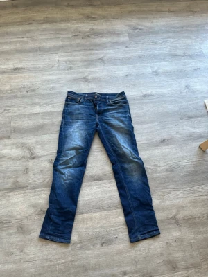 Jack and Jones Jeans - Snygga blå jeans med raka ben från Jack and Jones. Jeansen har en mörkblå tvätt med ljusare partier. Perfekta för en avslappnad stil. Storlek W29 o L30. Kom med prisförslag!