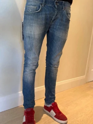 Blå slim fit jeans från Dondup - Säljer ett par blå skinny jeans från Dondup med klassisk femficksmodell och lätt slitna detaljer. Jeansen har en smal passform och är tillverkade i ett mjukt denimtyg som sitter snyggt på benen. Perfekta för en trendig och avslappnad look. OBS dondup lappen kommer tyvärr inte med