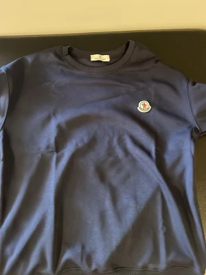 Mörkblå sweatshirt från Moncler - Snygg mörkblå sweatshirt från Moncler med rund halsringning och Moncler-logga på bröstet. Tillverkad i mjukt material som känns skönt mot huden. Perfekt för en avslappnad och stilren look.