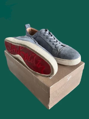 Ljusblå Louboutin skor - Snygga ljusblå sneakers från Christian Louboutin med klassisk låg profil och cool röd sula med logotyp. Skorna är gjorda i mocka och har vita gummisulor. Perfekt för dig som vill sticka ut med exklusiva detaljer. Perfekt för sommaren och de är i bra skick. Tveka inte på att höra av dig vid någon fundering. 