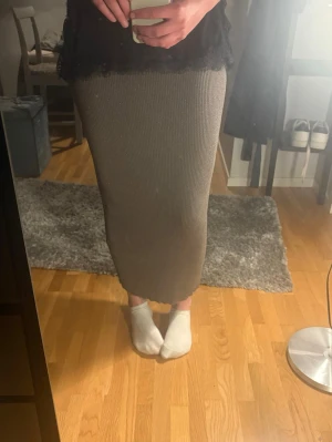 Beige ribbad långkjol - Säljer en beige ribbad långkjol med rak passform. Kjolen är enkel och stilren, perfekt att matcha med olika toppar. Materialet är mjukt och stretchigt vilket gör den bekväm att bära. Använd 1 gång säljer då den inte kommer til användning 