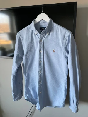 Ralph Lauren Skjorta - Säljer en Ralph Lauren skjorta i storlek S i en ljusblå färg. Skjortan är i ett väldigt fint skick och en eftertraktad färg🙌 Skriv vid funderingar!