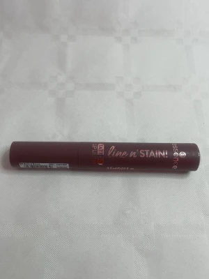 Essence line n' STAIN läppenna - Essence line n' STAIN Tattoo Lip Liner i en djup bärig nyans. Pennan har en smidig, rund form och är enkel att applicera för precisa läpplinjer. Förpackningen är i plast med metallic-rosa text. Perfekt för att skapa definierade läppar med långvarigt resultat.