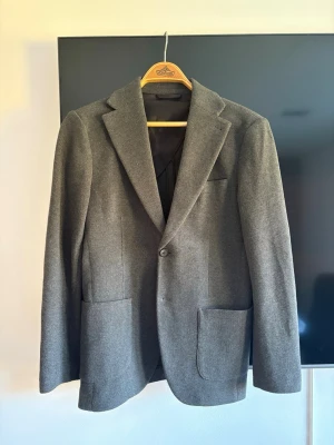 Grön/Grå kavaj från John Henric - Stilren grå kavaj från John Henric, köpt för 3 månader sedan men aldrig kommit till användning pga att den är för liten. Nypris runt 1500kr 